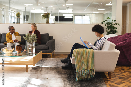 Diverse male and female colleagues working together in workplace lounge area photo