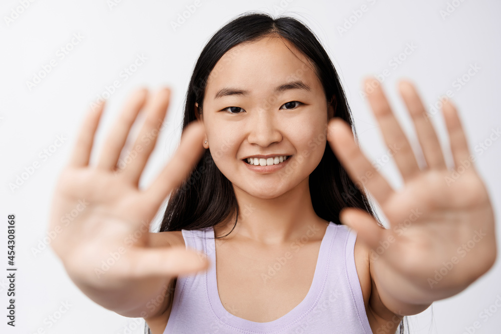 Beauty and wellbeing. Happy asian girl stretch out hands, showing empty palms and smiling, looking carefree at camera, white background Beauty and wellbeing. Happy asian girl stretch out hands, showing empty palms and smiling, looking carefree at camera, white background