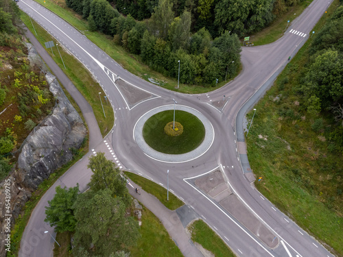 Bird's eye view of a traffic roundabout, roads, lanes with no cars and a path in Partille.  Aerial, drone photography taken from above in Sweden in summer. 
