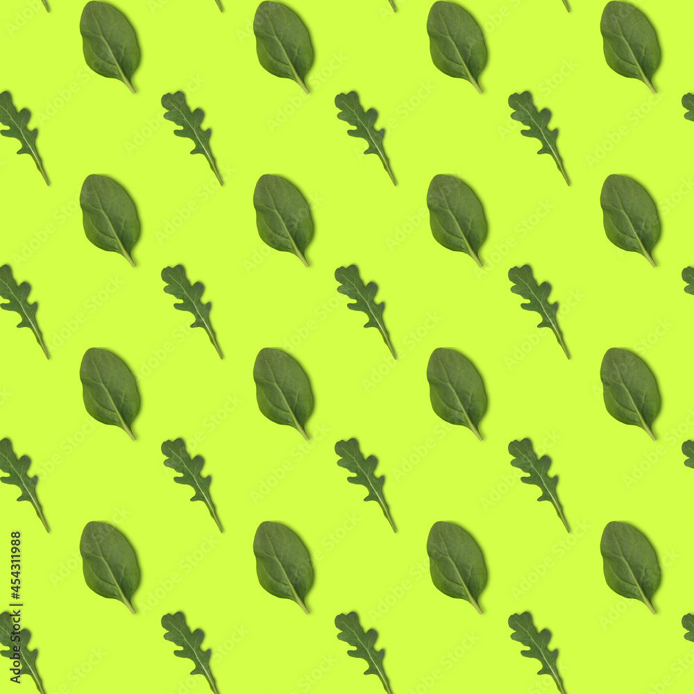 Seamless pattern with green arugula ans spinach isolated on yellow background, top view