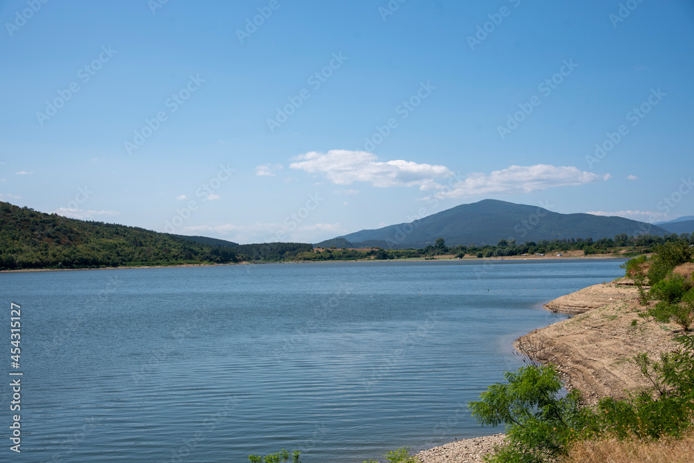 View of the blue lake against the background of the mountains on a clear sunny summer day.