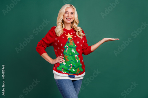 Photo of positive cheerful happy attractive woman hold hand empty space object isolated on green color background