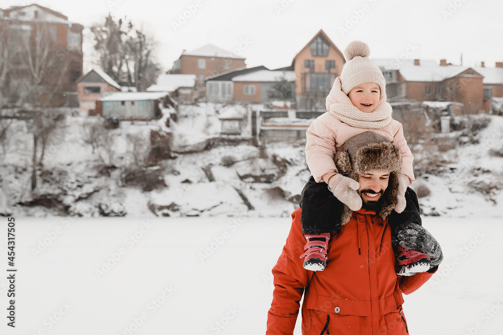 Young stylish bearded Father and baby Daughter On Winter Vacation. Father giving son ride on back in park. Happy, joyful family. Happy, joyful family.