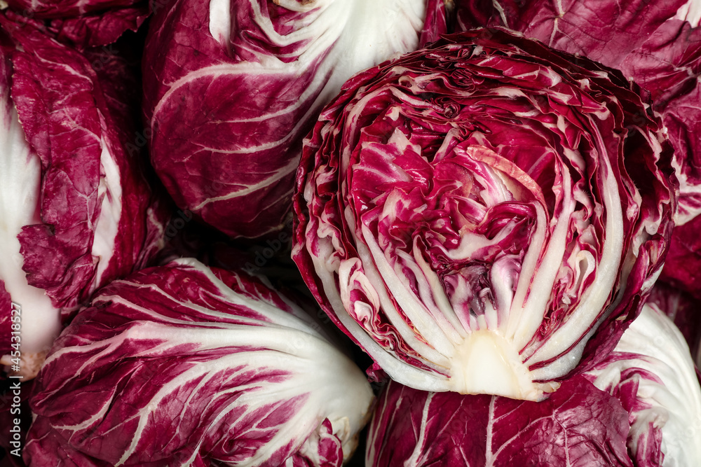 Obraz premium Whole and cut fresh ripe radicchios as background, top view