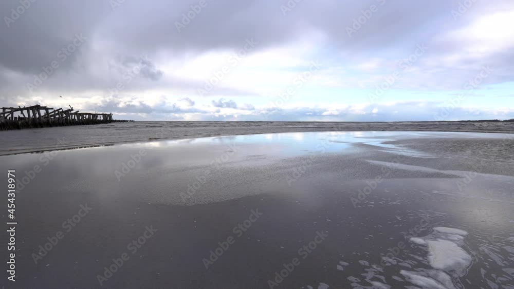 Old wooden breakwater ruins and its reflection on wet sand surface at Baltic sea coast near Sventoji village at cloudy sunset. Old wooden breakwater ruins and its reflection on wet sand surface at Baltic sea coast near Sventoji village at cloudy sunset.