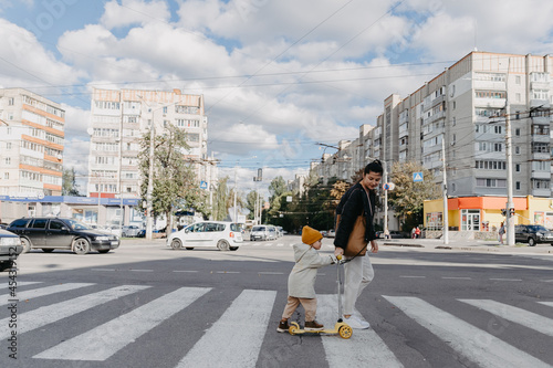 14.09.2020 Vinnitsa, Ukraine: mother brings a child riding a scooter on the crosswalk