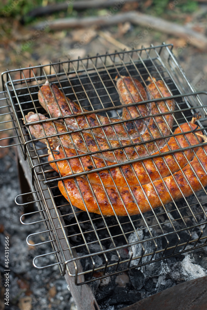 Delicious barbecue pork sausages flame grilled outdoor. Quick tasty campfire cooking. BBQ in the garden. Bavarian sausages