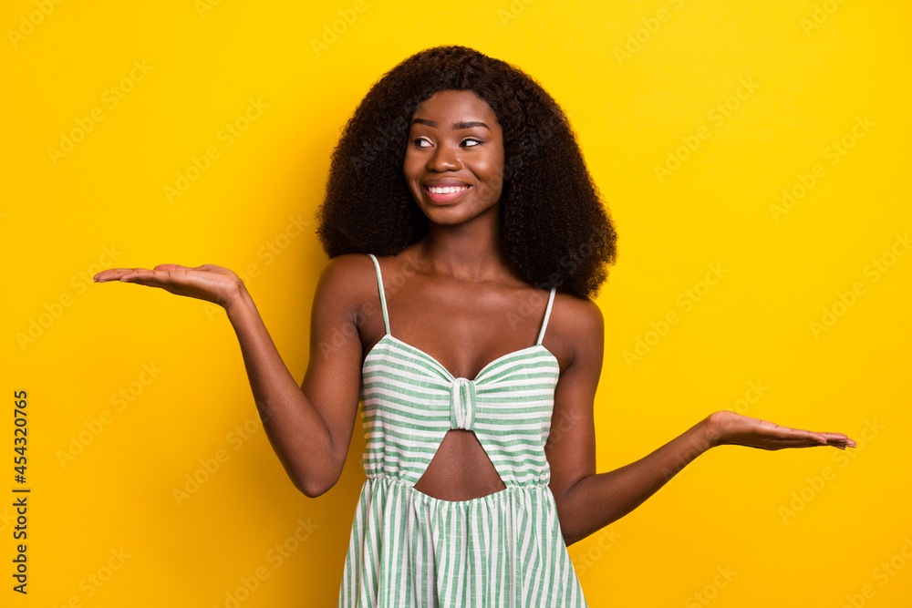 Photo of young african woman happy positive smile hold hands measure pros cons isolated over yellow color background Photo of young african woman happy positive smile hold hands measure pros cons isolated over yellow color background