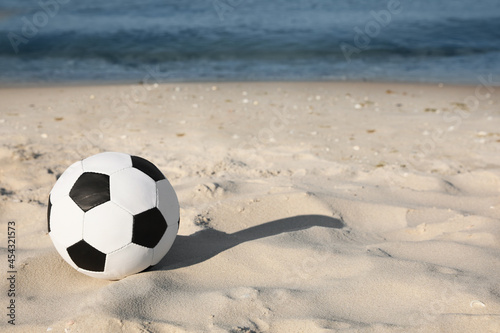Soccer ball on beach, space for text. Football equipment © New Africa
