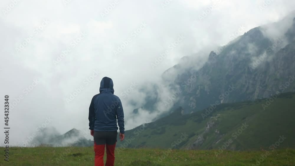 A lonely hiker admire the beautiful foggy landscape in the mountain A lonely hiker admire the beautiful foggy landscape in the mountain