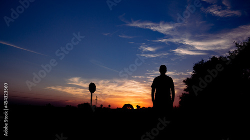 Silhouette of a man on a road watching the sunset. Concept of traveling on vacation. © Horacio Selva