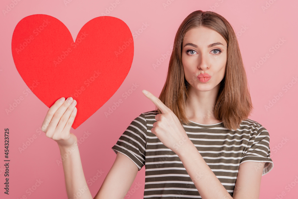 Portrait of romantic lady hold red heart card direct forefinger blow air kiss on pink background Portrait of romantic lady hold red heart card direct forefinger blow air kiss on pink background