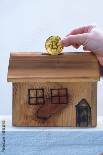 Little girl saving her bitcoin coin in her home piggy bank. Investing in the future with virtual money