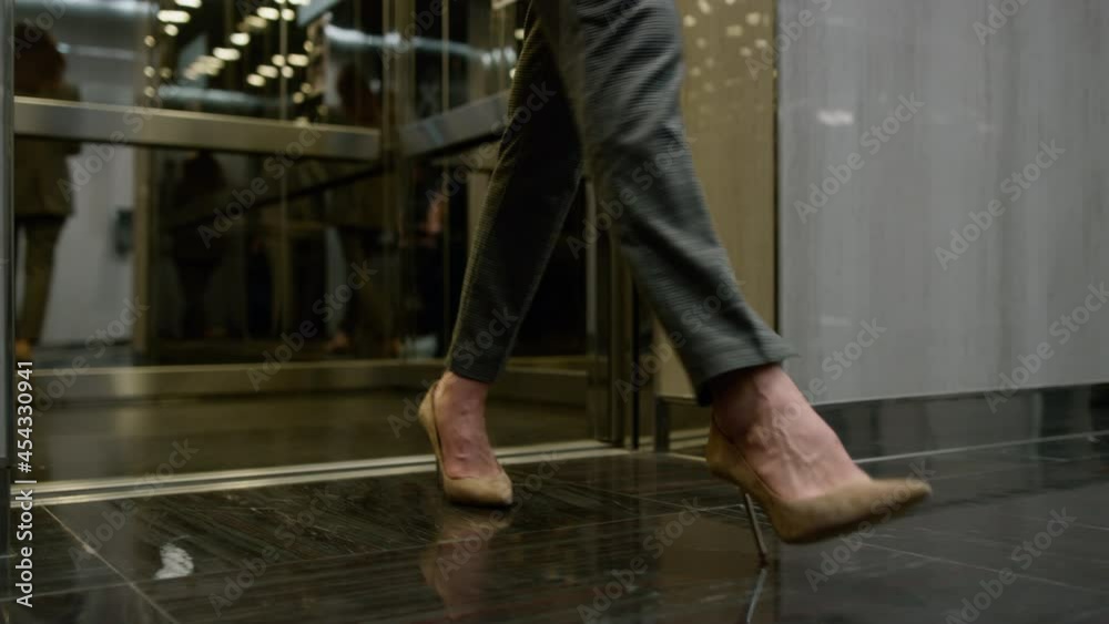 Businesswoman legs exciting elevator car. Business people going for work 