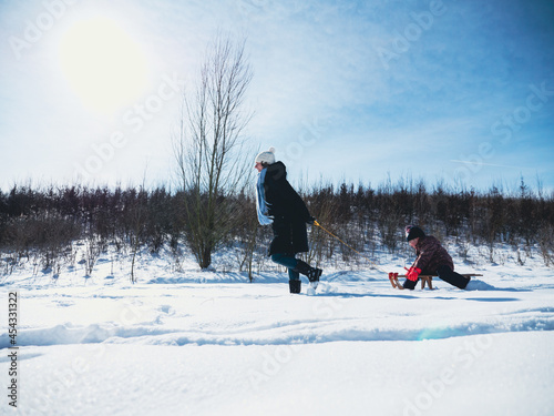 Mother pulling girl sitting in sled