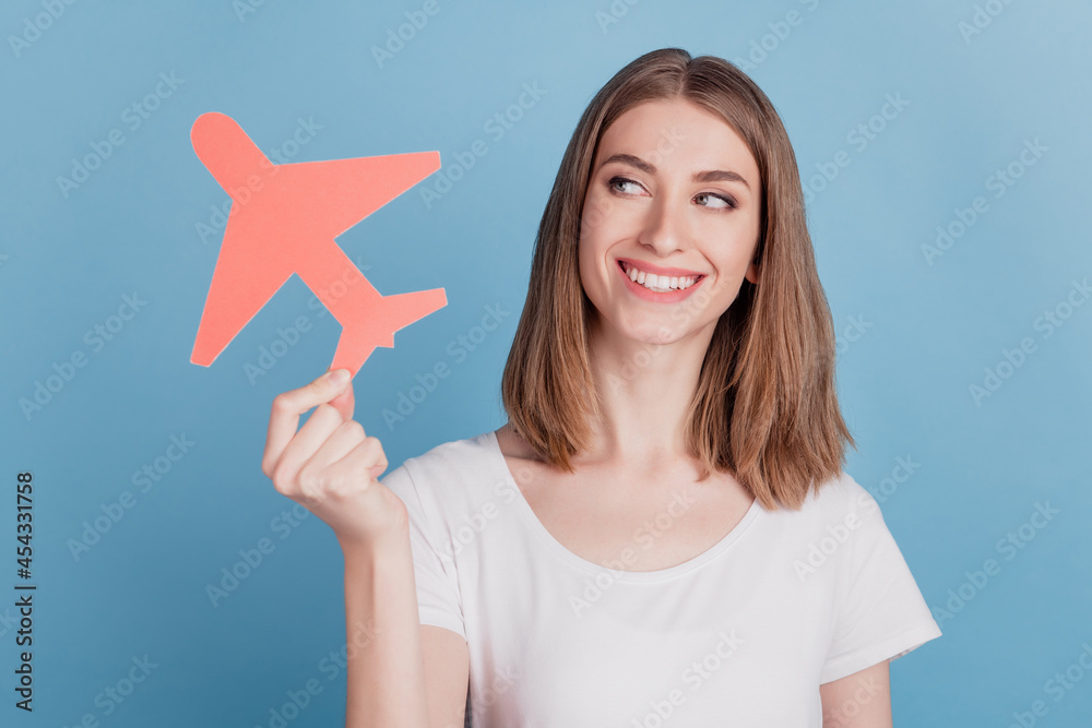 Portrait of interested lady hold paper plane look up empty space beaming smile on blue background Portrait of interested lady hold paper plane look up empty space beaming smile on blue background