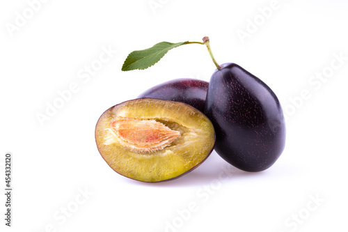 Plum with a slice and leaf on a white background.