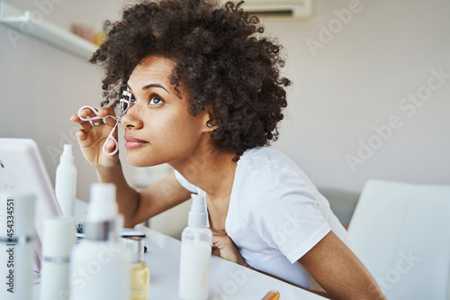 Concentrated serene lady using an eyelash curler