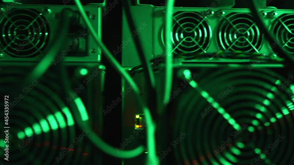 Bitcoin miners in large farm. ASIC mining equipment on stand racks mine cryptocurrency in steel container. Blockchain techology application specific integrated circuit datacenter. Server room lights.