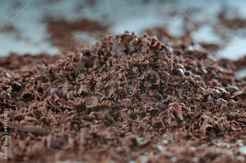 Grated chocolate on a white table. Preparation for dessert. The background in blur.