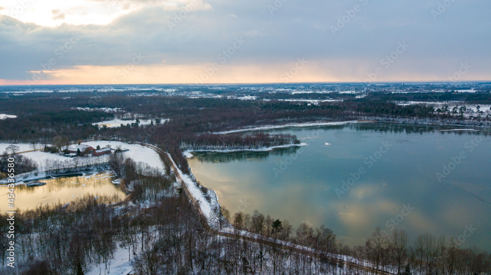 Aerial view of the winter snow covered forest and frozen lake from above captured with a drone. High quality photo