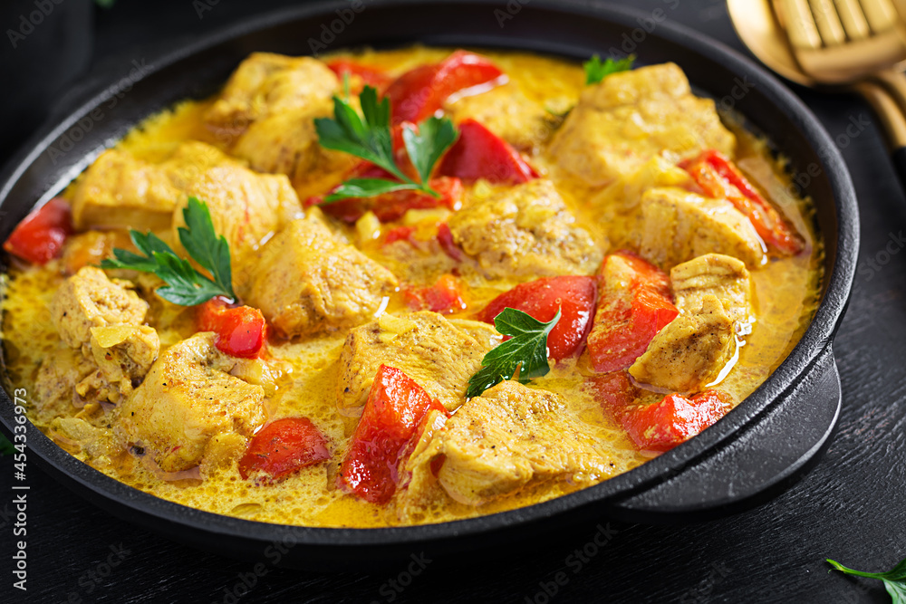 Traditional Indian curry chicken masala. Indian chicken curry with sweet peppers and  rice in bowl, spices, dark background. Traditional Indian dish.