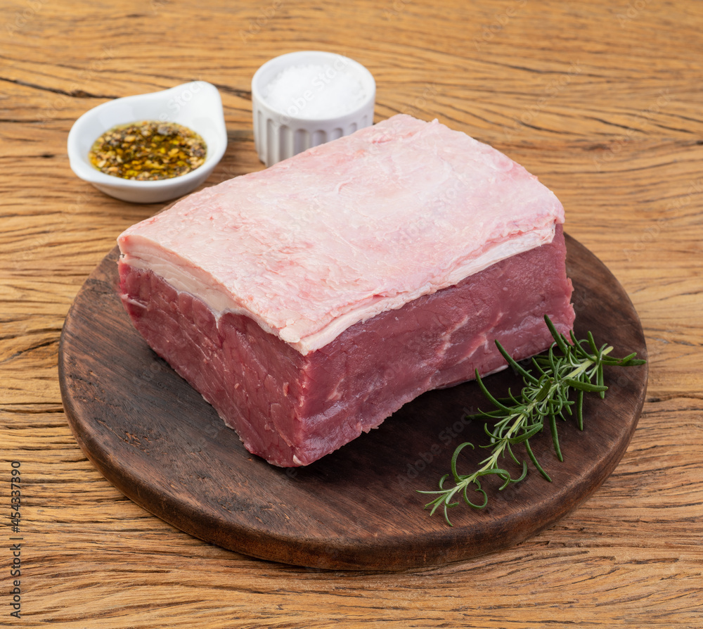 Raw ancho beef, typical argentinian cut, over wooden board with seasonings Raw ancho beef, typical argentinian cut, over wooden board with seasonings
