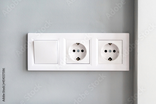 Foto White european electrical outlets and switch on gray wall