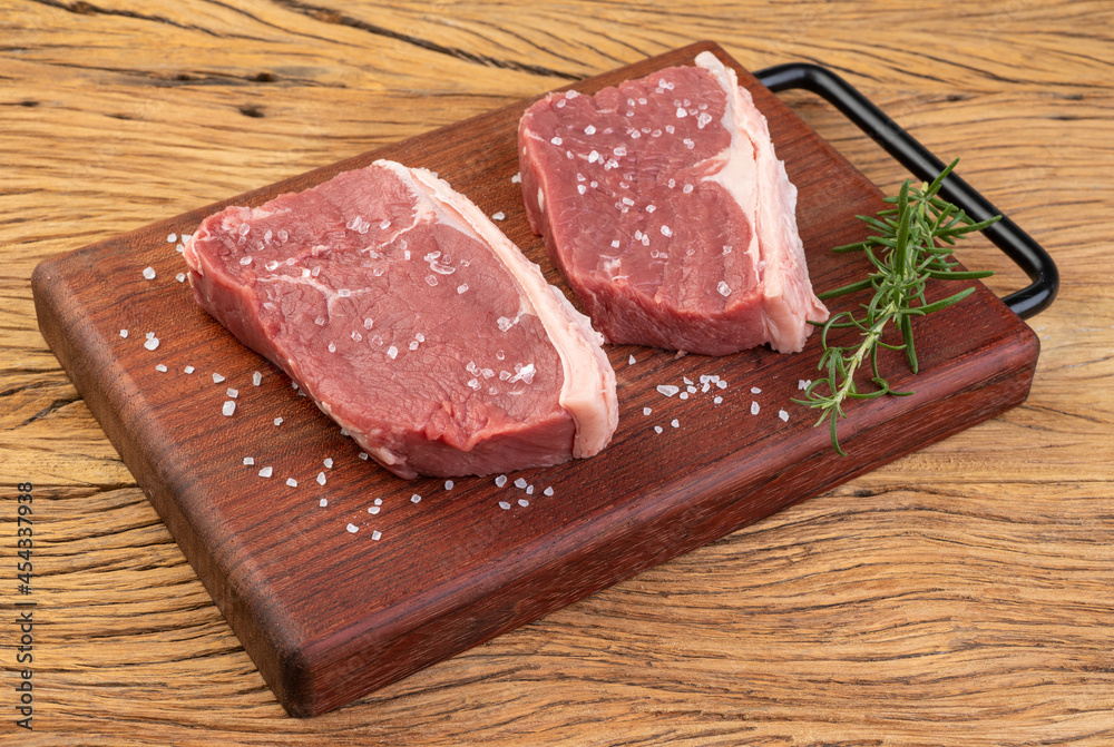 Sliced raw ancho beef, typical argentinian cut, over wooden board with seasonings Sliced raw ancho beef, typical argentinian cut, over wooden board with seasonings