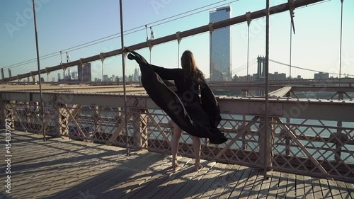Woman in black long flowing dress posing at Brooklyn Bridge in New York.