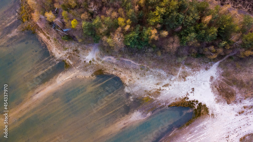 Aerial view shot by a drone of the shore of a forest lake. Thick grass, reflections in the water, green birches in the distance on the slope. Nature of the Blakheide, Beerse, Belgium. High quality photo