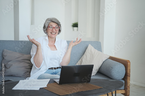 Happy enthusiastic overjoyed senior mature old woman received a joyful letter on laptop. Winning the lottery, sport betting and online casiono, gambling addiction of the elderly. photo