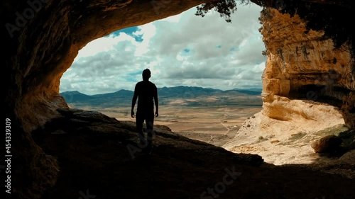 Friends inside cave against landscape. Romantic coupl Scenic rear view of a man and a woman walking in  outstanding caves against beautiful landscape in Cuevas de Zaen, Spain. Europe destinations.  photo