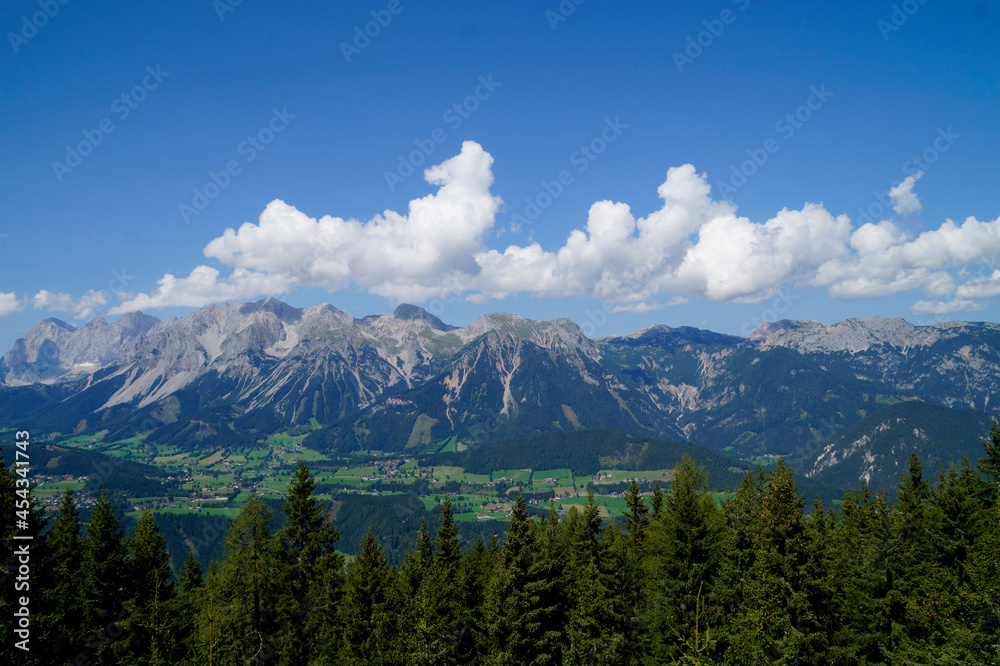 picturesque alpine panorama with a vast alpine valley of the Dachstein-Schladming region in the Austrian Alps against the blue sky with white fluffy clouds (Austria)