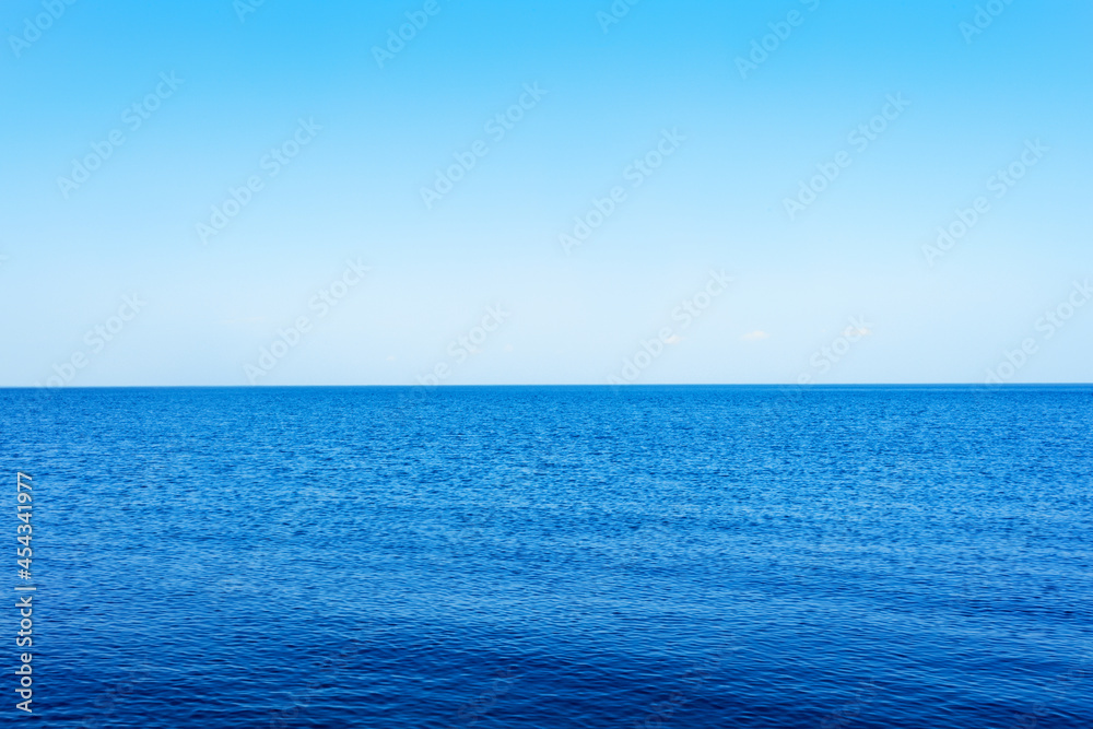 a calm blue lake against a clear sky with a horizon and a space for text.