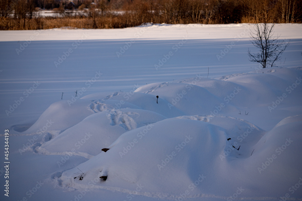 Texture of snowy nature on a winter day, white snow and shadows, snow formations look like hills. Animal footprints