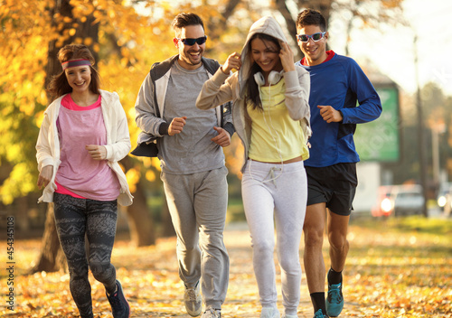 A group of young friends enjoys an invigorating jog in the park during a crisp autumn afternoon  surrounded by vibrant foliage.Autumn concept.