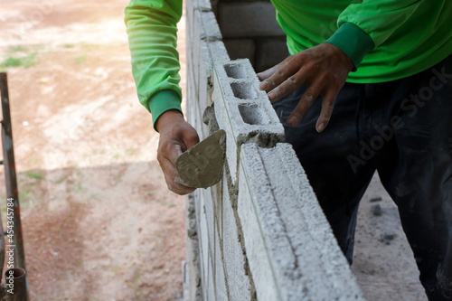 masonry worker make concrete wall by cement block and plaster at construction site