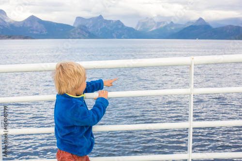 Fotografia Child, cute boy, looking at the mountains from a ferry in Nortern Norway on his