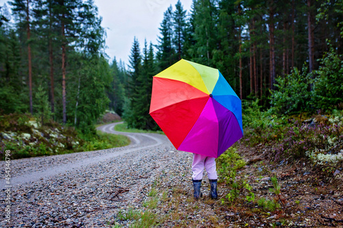 Cute toddler child with colorful umbrella  playing in the forest on a rainy day
