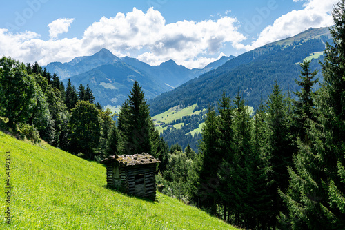 Traditional hay barn on a green meadow in the Tyrolian Alps in Austria on a sunny summer day