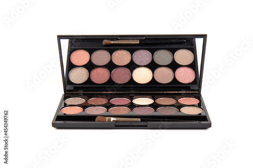 Eyeshadow palette. Black plastic case with twelve powder matte, glitter paint sample in purple, pink, brown, vanilla colors and brush. Top view makeup box isolated on white background