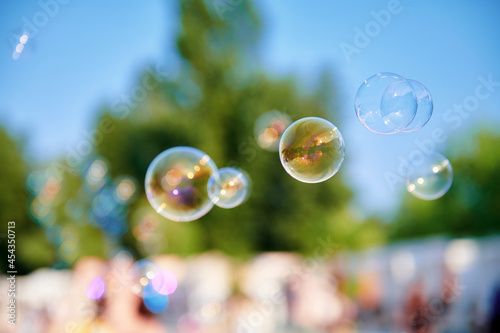Beautiful soap bubbles at the park on a sunny day. A lot of bubbles in the air. Blurred background. Childhood concept photo. Large size image.