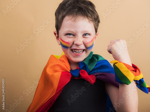 Smiling boy with rainbow flag and striped makeup photo