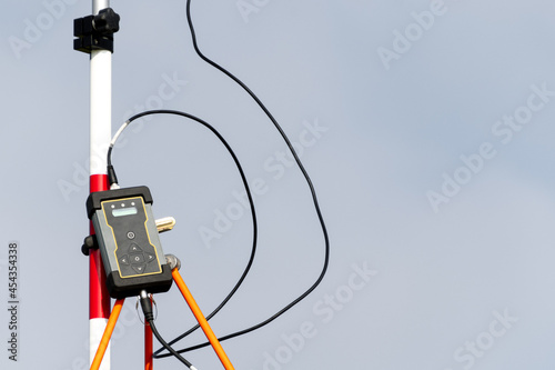 ein Entfernungsmesser mit Laser Technik ist an einer rot weißen Schiene befestigt und mit zwei schwarzen Kabeln verbunden photo