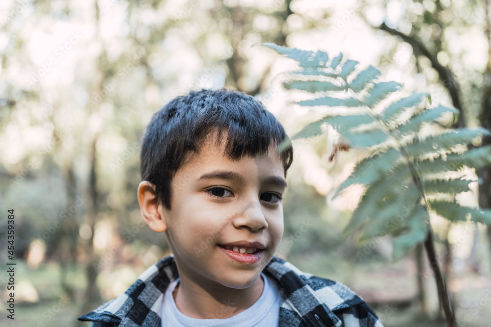 Boy with leaf looking at camera in forest Boy with leaf looking at camera in forest