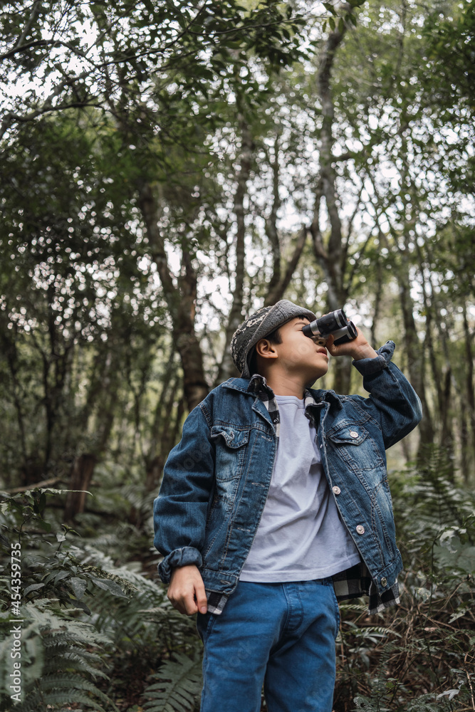 Ethnic boy looking through binoculars in summer forest Ethnic boy looking through binoculars in summer forest