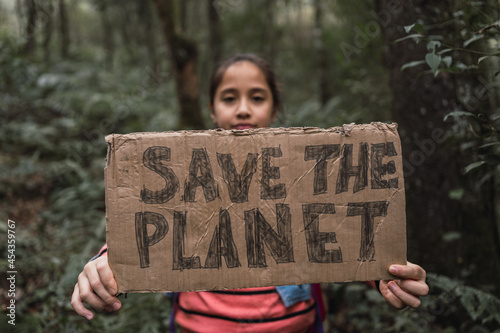 Ethnic girl showing Save The Planet title in summer woods photo