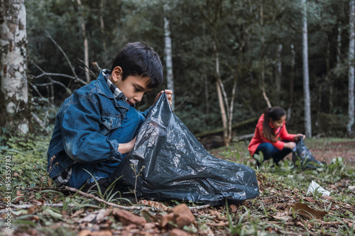 Ethnic children collecting garbage from land in forest