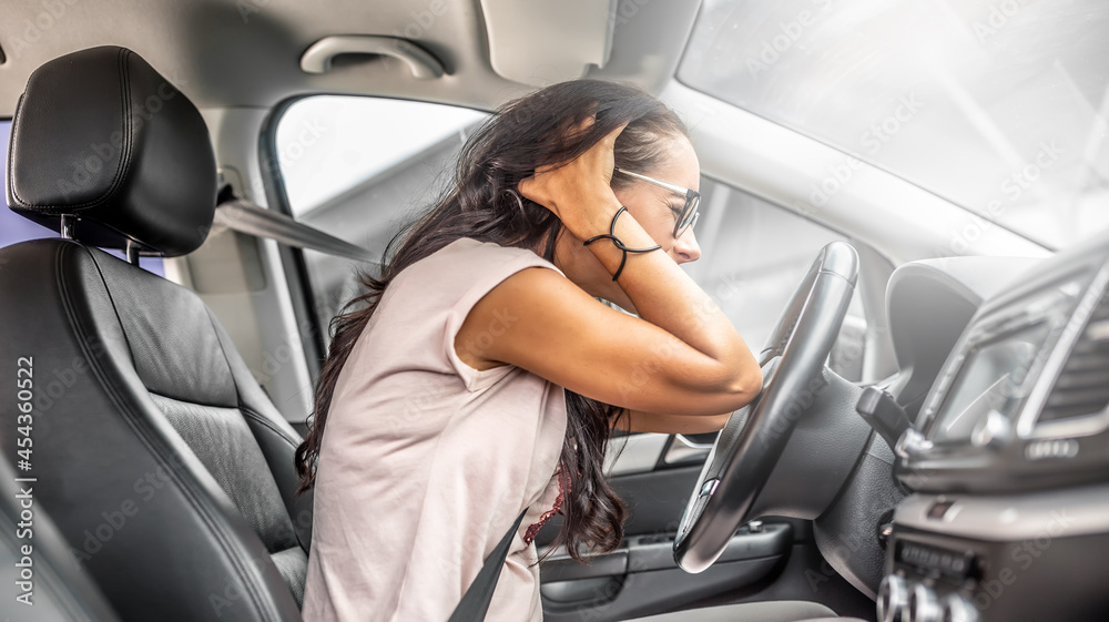 Female driver with headache or in desperation holds her head with both hands sitting on a driver's seat